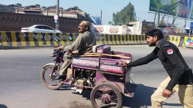 ایک پولیس اہلکار معذور افراد کی گاڑی کو دھکا لگا رہا ہے