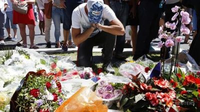 A man reacts near bouquets of flowers in Nice France